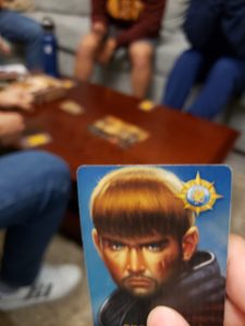 A hand holding up the Percival card in a game of Avalon. 